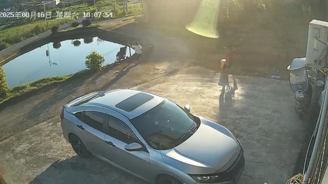 鱼塘边女子只顾与人聊天，婴儿车顺斜坡翻落水中